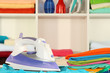 Clothes and iron on table on shelves background