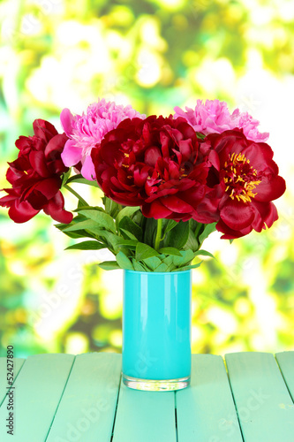 Photo: Beautiful peonies in vase on table on bright background Beautiful peonies in vase on table on bright background