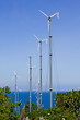 Series of wind power generators in clear blue sky background.