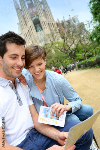 Photo: Couple reading travel guide by the sagrada familia church Couple reading travel guide by the sagrada familia church