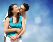 Photo: Beautiful couple kissing on blue sky background Beautiful couple kissing on blue sky background