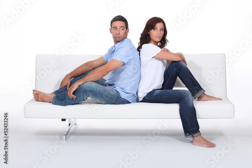 Photo: Couple back to back on white sofa Couple back to back on white sofa