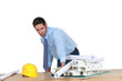 Annoyed architect piling rolled-up drawings on a model