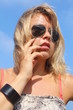 Blond young woman touching her lips, outside