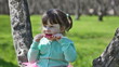 Little girl in a turquoise jacket eats sugar candy