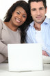 Mixed couple sat with laptop