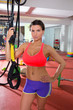 Crossfit fitness woman standing at gym holding trx