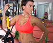 Crossfit fitness woman standing at gym holding trx