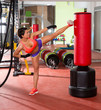 Foto: Crossfit woman kick boxing with red punching bag Crossfit woman kick boxing with red punching bag
