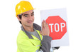 young bricklayer wearing safety jacket and stop sign