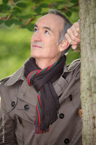 Photo: Retired man leaning against a tree Retired man leaning against a tree