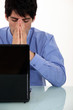 young businesswoman seated in front of laptop looking exhausted