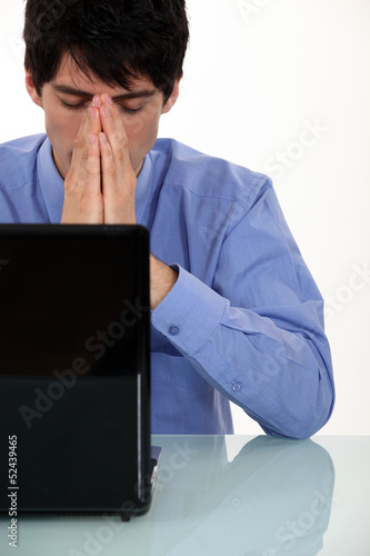 Photo: young businesswoman seated in front of laptop looking exhausted young businesswoman seated in front of laptop looking exhausted