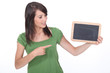 Foto: Young woman pointing at a blank blackboard Young woman pointing at a blank blackboard