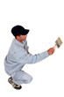 Squatting tradesman painting a wall