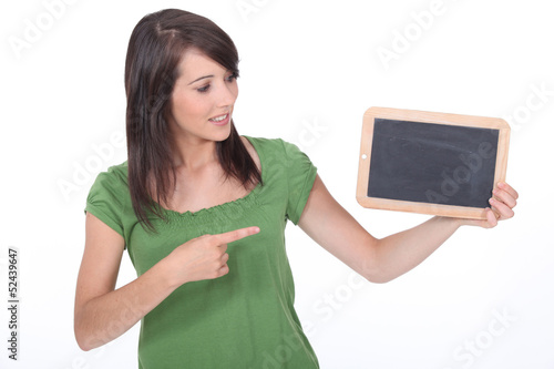 Photo: Young woman pointing at a blank blackboard Young woman pointing at a blank blackboard