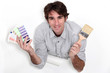 Photo: Man holding colour samples and a paintbrush Man holding colour samples and a paintbrush