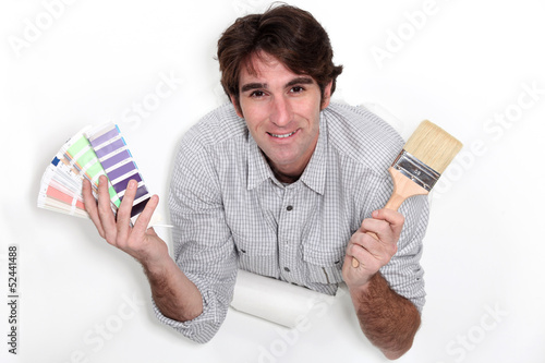 Photo: Man holding colour samples and a paintbrush Man holding colour samples and a paintbrush