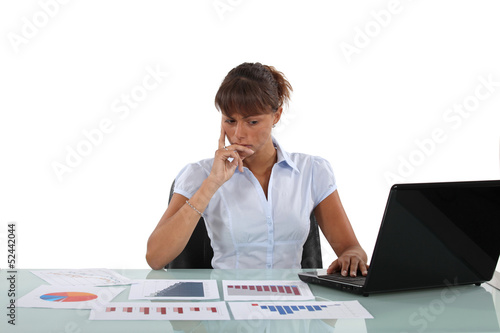 Photo: Woman sat at desk surrounded by graphs Woman sat at desk surrounded by graphs