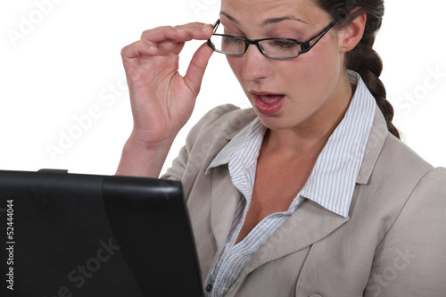 Photo: Woman looking in surprise at her laptop Woman looking in surprise at her laptop