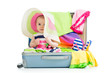Baby girl sitting in suitcase with  things for vacation travel