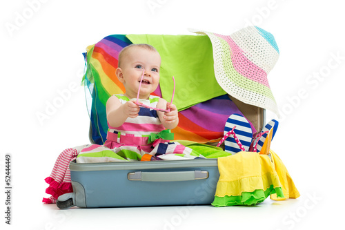 Photo: Baby girl sitting in suitcase with things for vacation travel Baby girl sitting in suitcase with things for vacation travel
