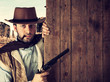Bad gunman indicates with the gun a wooden plank