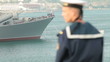 Sailor looking at moored navy ship