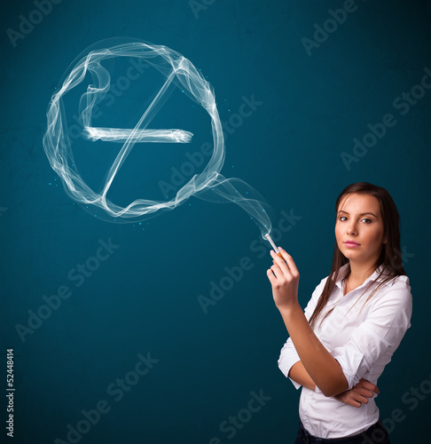 Photo: Young lady smoking unhealthy cigarette with no smoking sign Young lady smoking unhealthy cigarette with no smoking sign