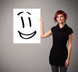Foto: Young woman holding smiley face drawing Young woman holding smiley face drawing