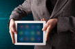 Photo: Businessman holding a white modern tablet with blurry apps Businessman holding a white modern tablet with blurry apps