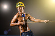 Nude builder pulling rope in darkness