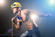 Nude builder pulling rope in darkness
