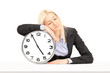 Tired businesswoman sleeping on a wall clock at workplace