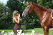 Beautiful girl in dress and horse portrait near the flower bed