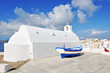 Traditional whitewashed chapel and small boat in Oia