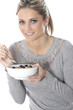 Model Released. Young Woman Eating Breakfast Cereal with Fruit