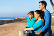 little girl pointing at ocean with parents