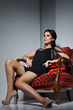 Sexual  girl with dark hairs, sitting on a red arm-chair