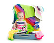 Foto: Baby girl sitting in suitcase with things for vacation travel Baby girl sitting in suitcase with things for vacation travel