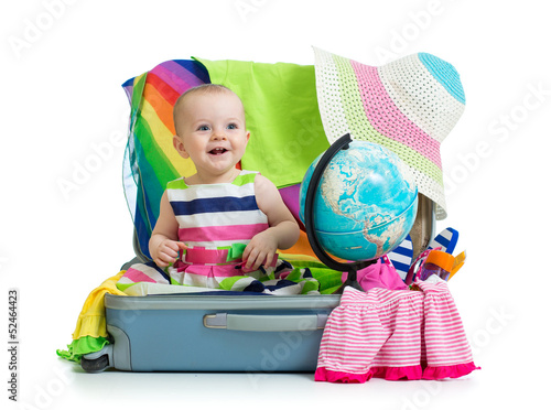 Photo: Baby girl sitting in suitcase with things for vacation travel Baby girl sitting in suitcase with things for vacation travel