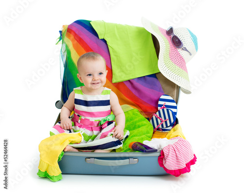 Photo: Baby girl sitting in suitcase with things for vacation travel Baby girl sitting in suitcase with things for vacation travel