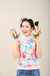 Young pretty painter with hands in paint, on gray background