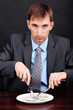 Young businessman having dinner dollars on black background