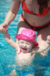 A little girl bathing in the pool in her mother's arms