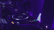 Nightclub DJ pushes buttons on a turntable, vinyl record playing