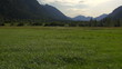 aerial flight close above meadow and stream with mountains