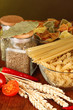 Photo: Different types of pasta, spices, tomatoes on a wooden table Different types of pasta, spices, tomatoes on a wooden table