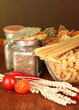 Photo: Different types of pasta, spices, tomatoes on a wooden table Different types of pasta, spices, tomatoes on a wooden table