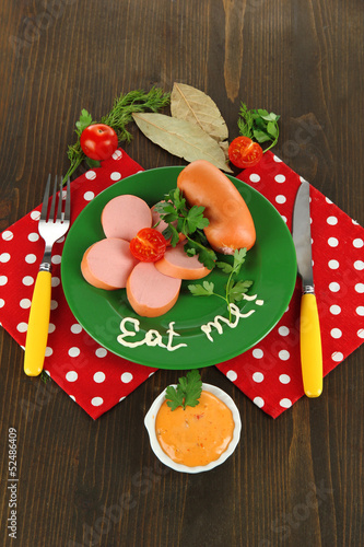Photo: Sausage, greens, tomato on plate on wooden table Sausage, greens, tomato on plate on wooden table